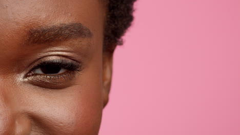 close-up of an eye with makeup on a pink background