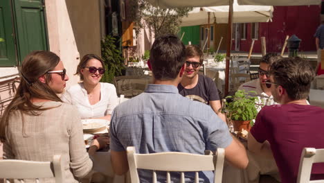 group of friends enjoying lunch outdoors in italy