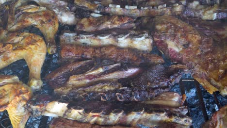 partially cooked chicken and beef meat roasting slowly in a traditional asado, argentina