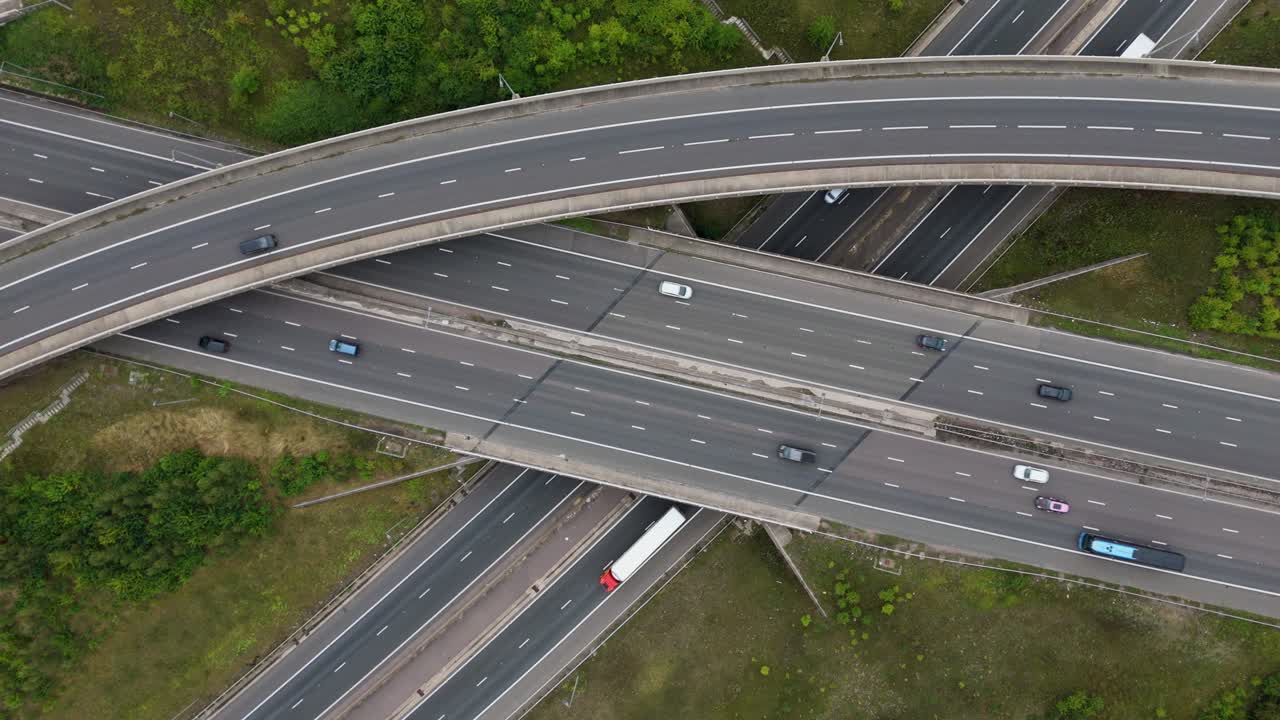 Wide aerial drone view of busy motorway interchange with vehicles navigating flyovers and junctions near Birmingham England UK