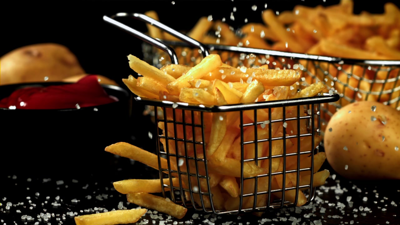 Sale che cade su patatine fritte appena cotte al rallentatore