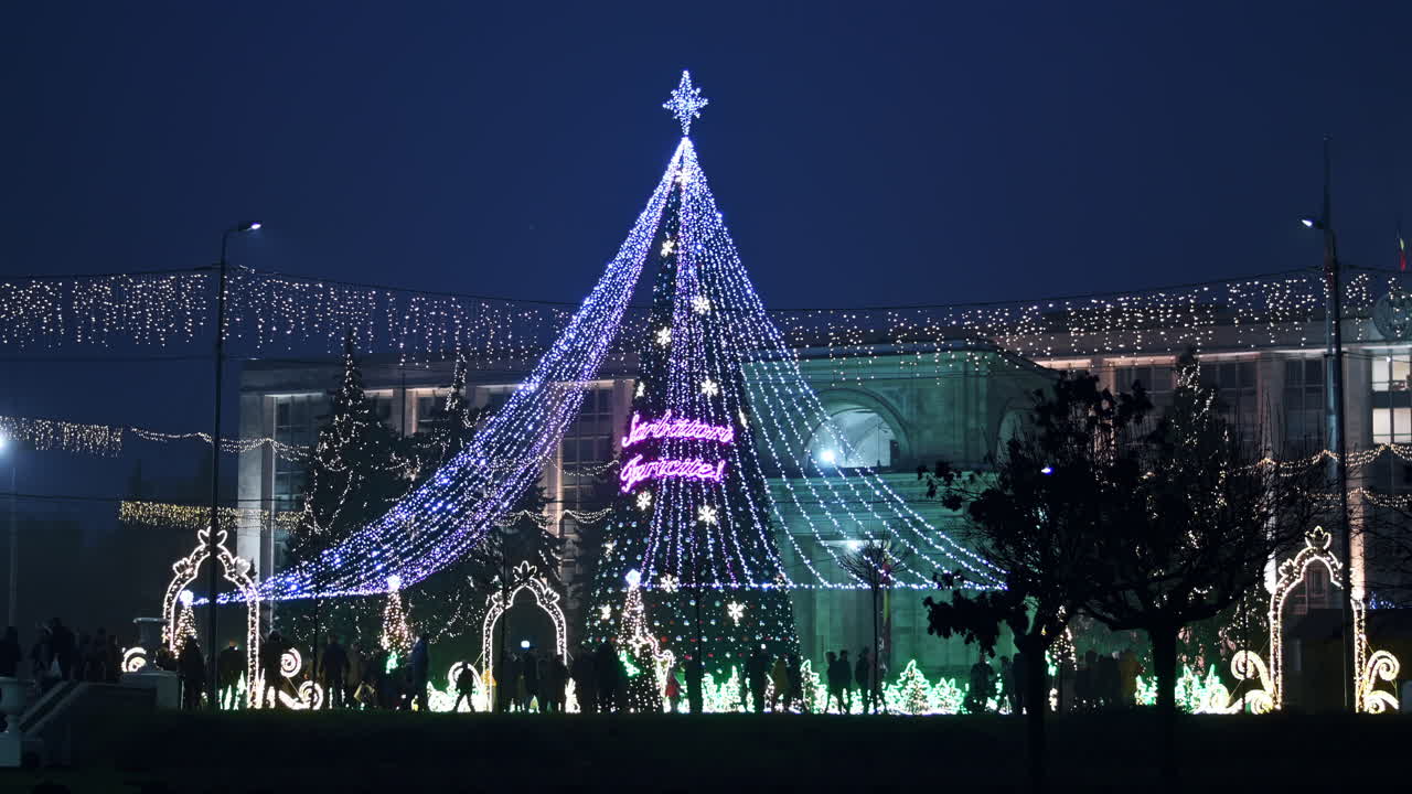 Chisinau, Moldova - December 20, 2021: Festive lights shine brightly as crowds gather around a beautifully decorated Christmas tree in the city center, creating a joyful holiday atmosphere at night