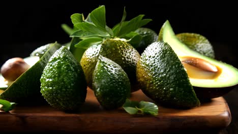 fresh avocados sliced open with green leaves on a wooden cutting board