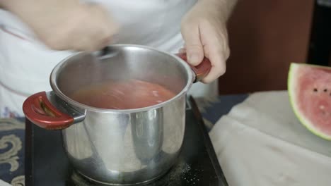 Vista-Frontal-Del-Chef-Batiendo-Una-Olla-De-Metal-Para-Hacer-Gelo-Anguria-En-Un-Plato-Caliente.