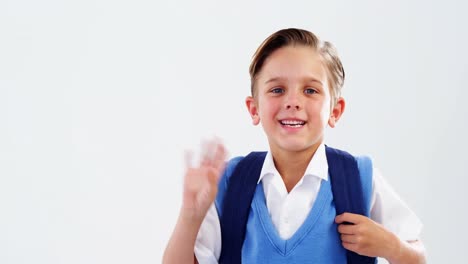 porträt eines lächelnden schuljungen, der mit der hand winkt