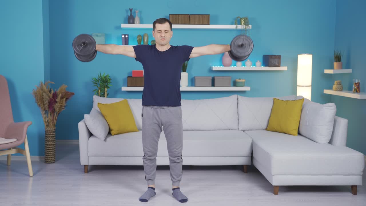 보디빌더 남자가 집에서 다양한 움직임에 덤벨을 사용합니다.
