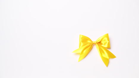 detail of male hand holding ribbon in yellow color on white background