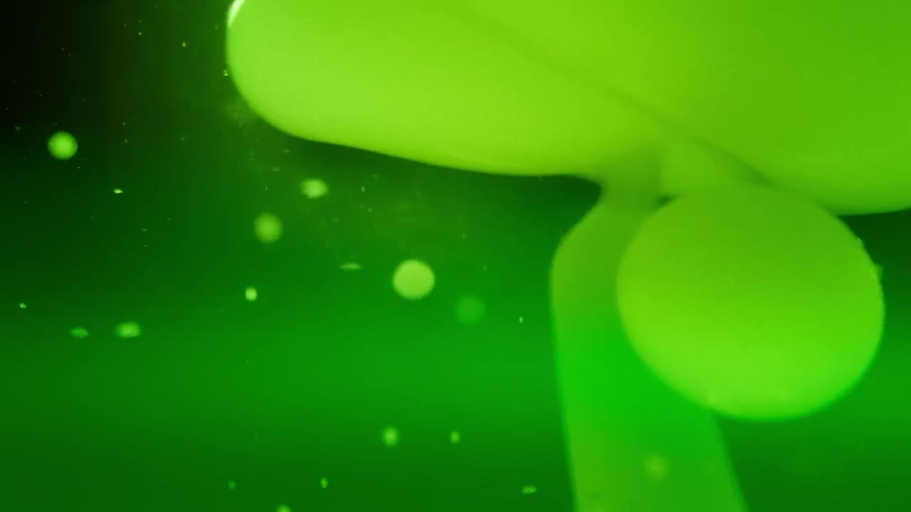 Bolle verdi cangianti che fluttuano in un liquido su uno sfondo sfumato.