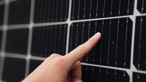 dedo corriendo por la superficie de un panel solar comprobando su eficiencia