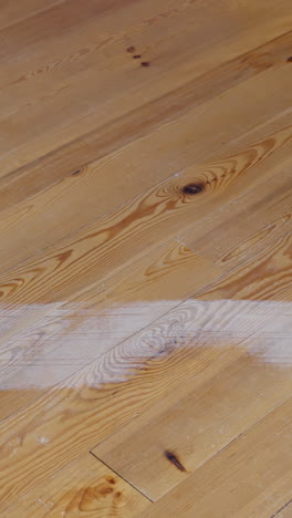 man sanding pine wood floor, close-up of legs, showing cleaning and restoration process