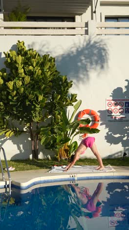 mujer haciendo yoga junto a la piscina