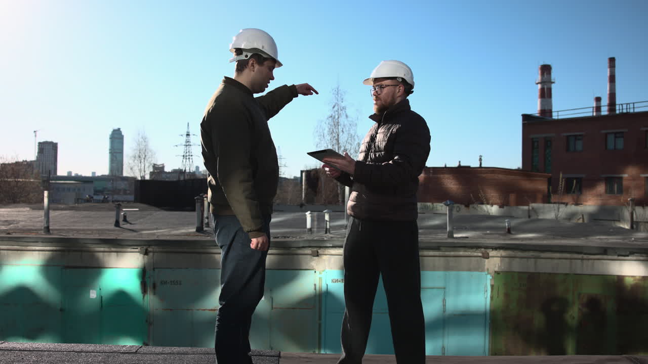 Twee belanghebbenden bespreken ontwerp op dakterras, manager wijst naar skyline, klant bekijkt tabletnotities.