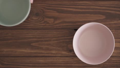 female hands put three empty bowls on a wooden textured table. three bowls next to each other on the kitchen table