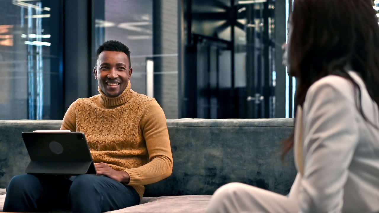 Black man working using a tablet while talking with a woman in an office. Slow motion