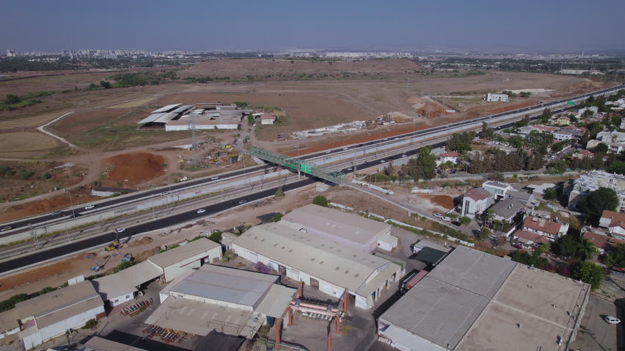 paralaje aéreo de un puente agrícola verde sobre una carretera principal, casas residenciales por un lado y áreas agrícolas por el otro