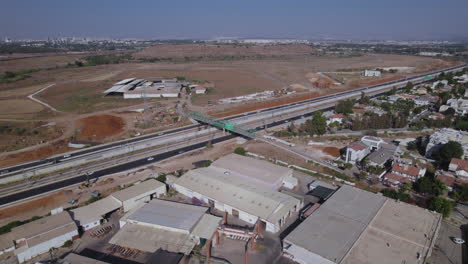 Luftparallaxe-Einer-Grünen-Landwirtschaftlichen-Brücke-über-Eine-Hauptstraße,-Wohnhäuser-Auf-Der-Einen-Seite-Und-Landwirtschaftliche-Flächen-Auf-Der-Anderen