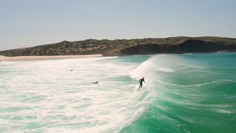 Aerial:-Surfing-the-beach-of-Bordeira-in-the-Algarve,-Portugal