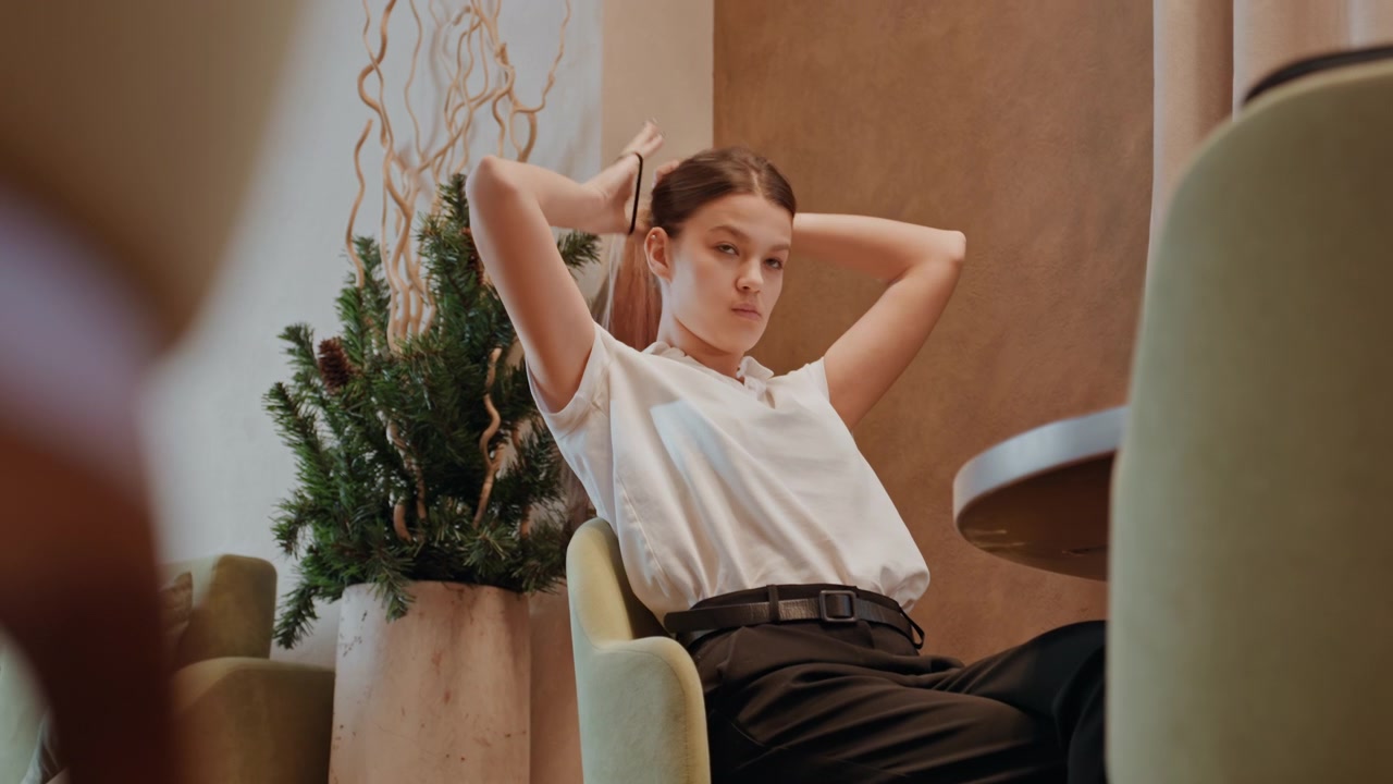 White woman reclining in relaxed reflection, soft chair and green plant, slow breath, eyes closed then open, mindful pause after work, daydreaming mood, introspective posture, warm tones, gentle