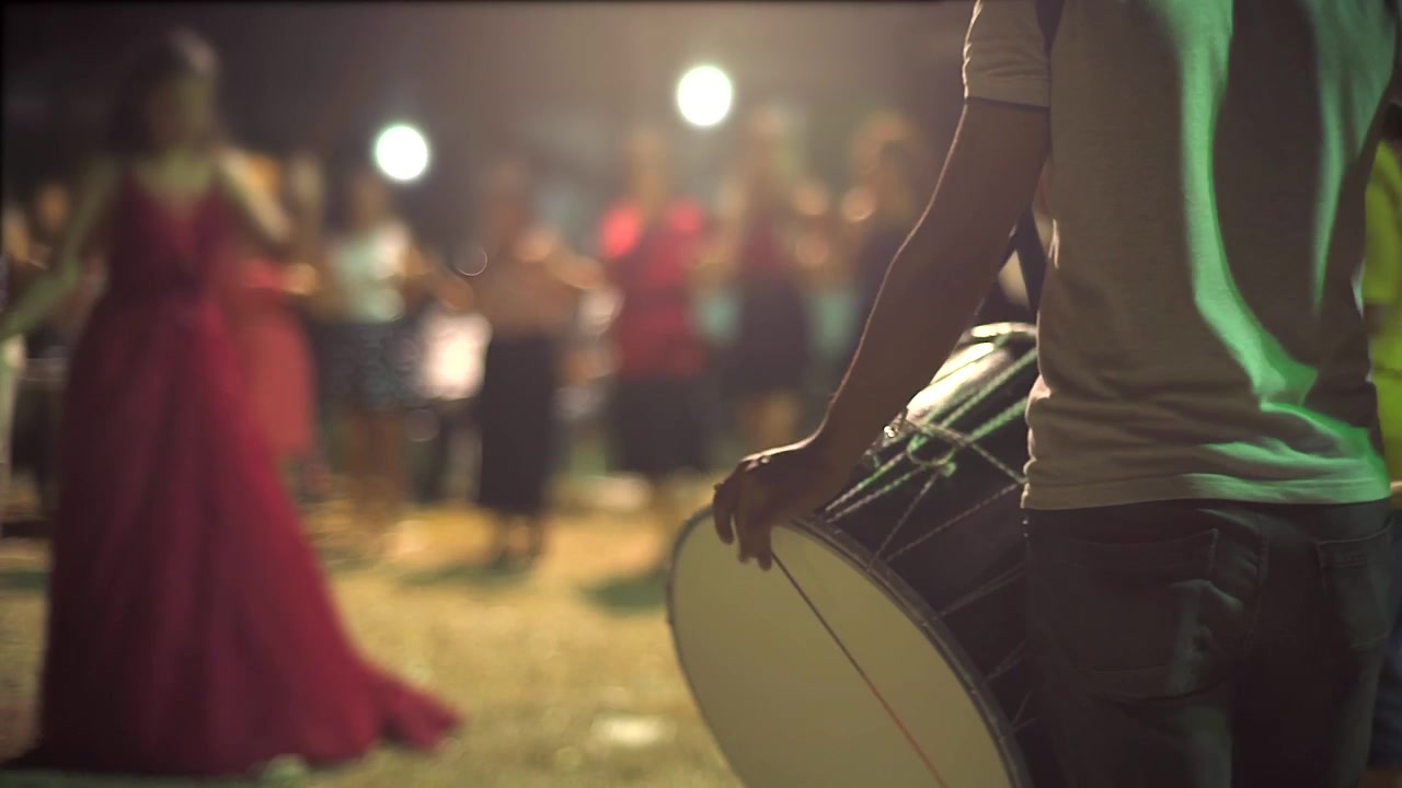 Musician Playing Traditional Drum at Outdoor Evening Celebration