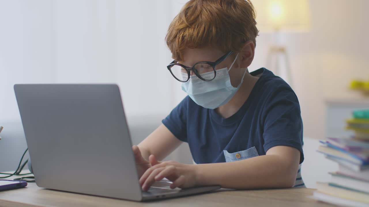 ребенок, изучающий онлайн дома, носящий маску