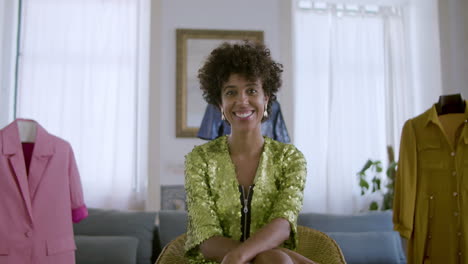 hermosa mujer negra sentada en casa, sonriendo a la cámara