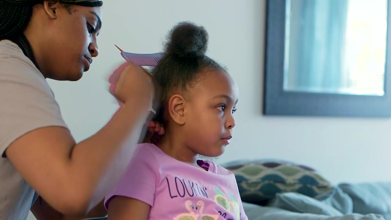 Primo Piano Medio di una Ragazza Afroamericana che si Fa le Trecce ai Capelli a Casa Durante l'Ordinanza di Restare a Casa