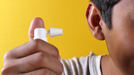 close up of men using spray to remove earwax