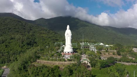 aerial drone view of tall lady buddha statue and temples with huge mountains and ocean in da nang, vietnam