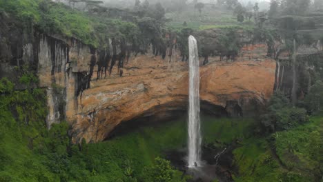 a forward moving aerial shot towards sipi falls pouring into a lush green valley in africa