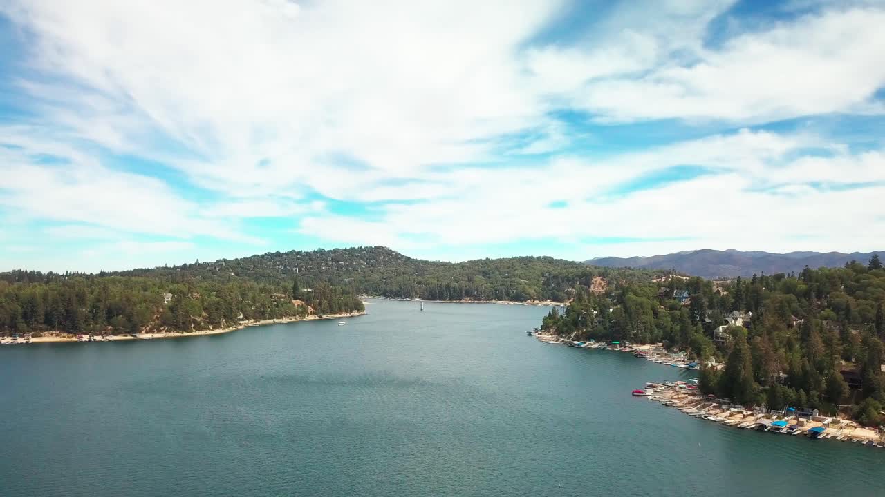 Wide descending aerial shot of a pristine mountain lake on a clear day. 4K