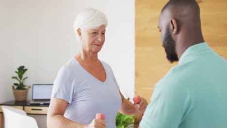 video of happy african american male physiotherapist examining caucasian senior woman