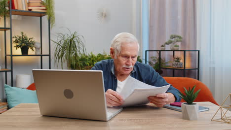 Stressed-senior-man-looking-at-unpaid-bank-debt-loan-doing-paperwork-planning-budget-throws-bills