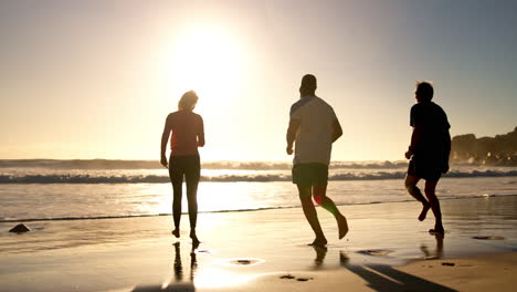 people running on the beach at sunset
