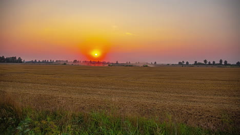 cinematic time lapse footage of farm workers driving tractors on a field while the sun is setting in the background, timelapse