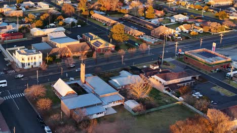 drone footage captures a sweeping aerial view of coonabarabran, new south wales, during golden sunset light, highlighting streets, buildings, and residential areas