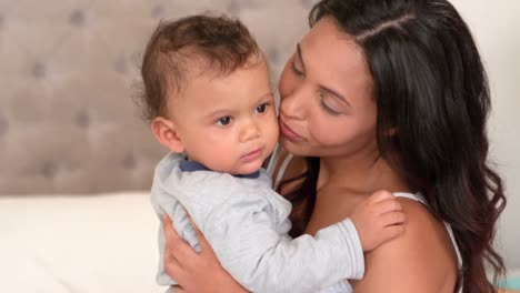 madre con un bebé lindo sentado en la cama