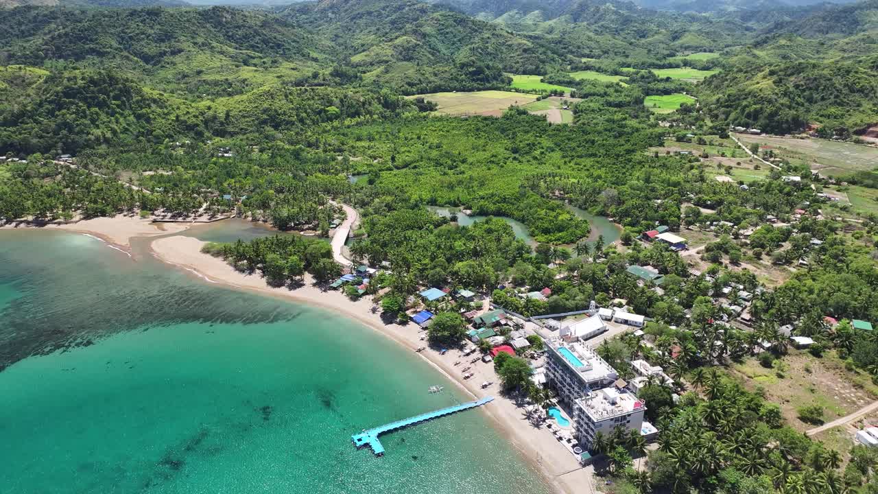 A remote village on busuanga island with lush green hills and a beach, aerial view