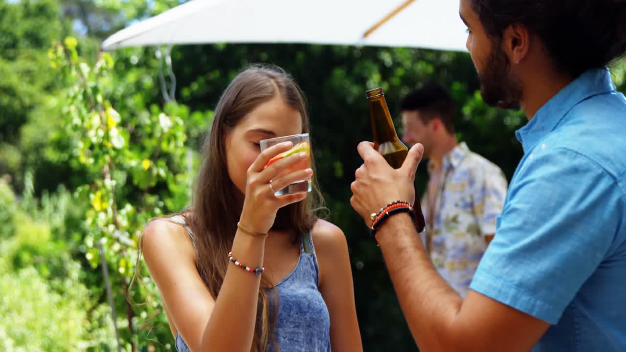 amigos interactuando entre sí mientras beben en una fiesta de barbacoa al aire libre