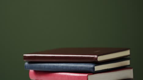 Close-up-of-stack-of-books-with-copy-space-on-green-background