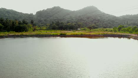 lake-birds-eye-view-transmission-tower-power-grid-power-line-by-the-lake-over-the-mountain-reflection-in-rippling-lake-water