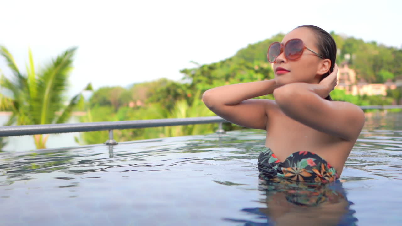 Classy Natural Exotic Woman Touching Wet Hair in Swimming Pool of Luxury Tropical Resort