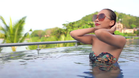 Classy-Natural-Exotic-Woman-Touching-Wet-Hair-in-Swimming-Pool-of-Luxury-Tropical-Resort