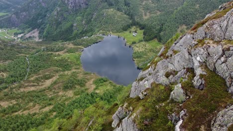 lago de agua dulce leirovatnet visto desde un alto acantilado en la cima de la montaña - antena moviéndose lateralmente cerca del acantilado creando un efecto de paralaje masivo - vista impresionante eidslandet vaksdal noruega