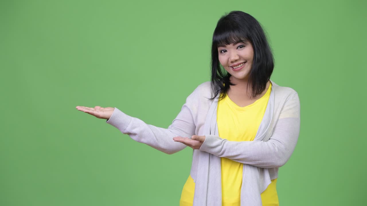 Beautiful happy Asian woman showing something