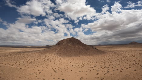 con nubes de ensueño del desierto de mojave, un gran cerro domina el paisaje - vista aérea ascendente hacia abajo