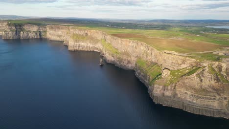 drone shot flying towards the cliffs of moher at sunset