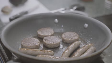 a slowed down shot of sausage sizzling in a frying pan