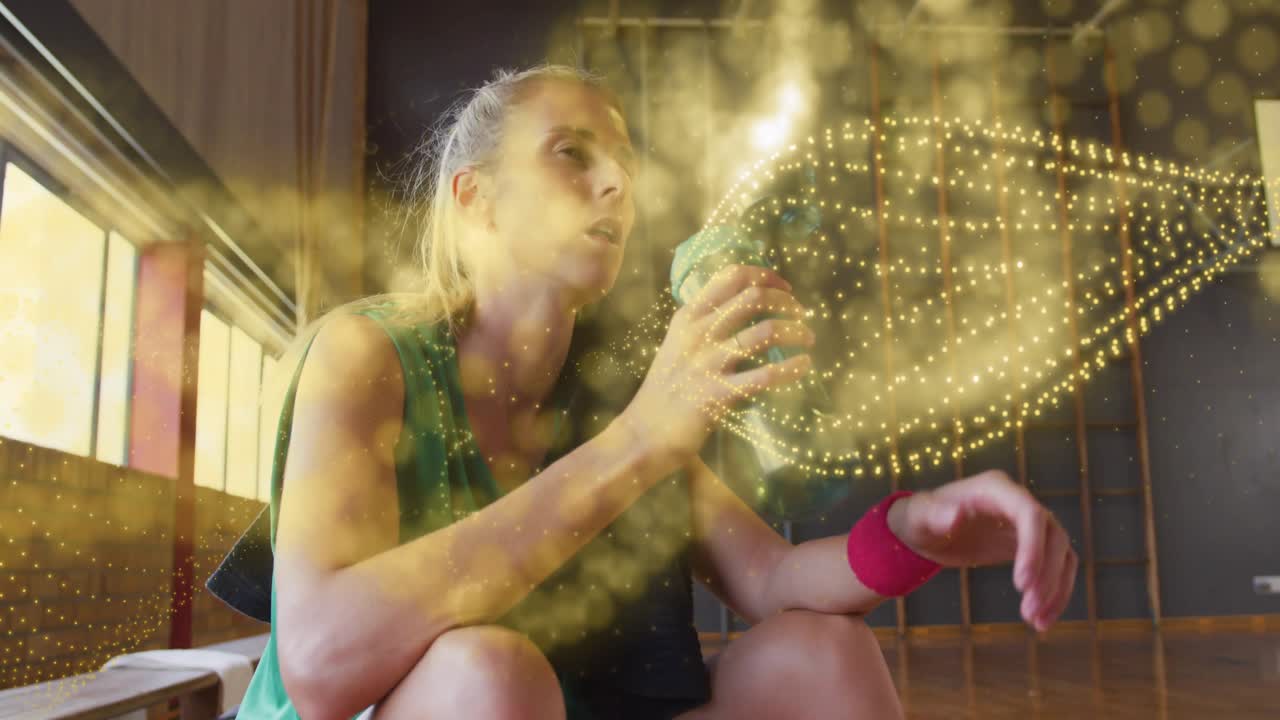 Atleta che apre la cerniera della borsa e svita il tappo della bottiglia, sorseggiando mentre particelle dorate vorticano, per il fitness