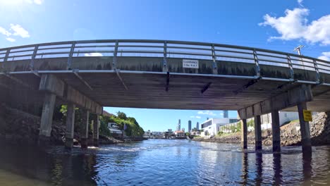 barco pasando bajo un puente con vista a la ciudad