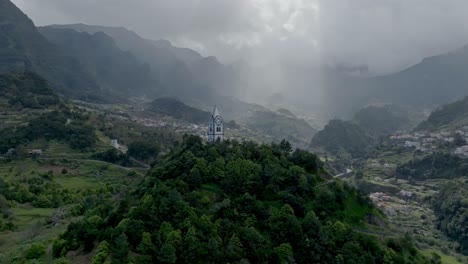 Drone-pulls-back-from-white-timberlined-clock-tower-of-San-Jorge-Church-Maderia-Portugal